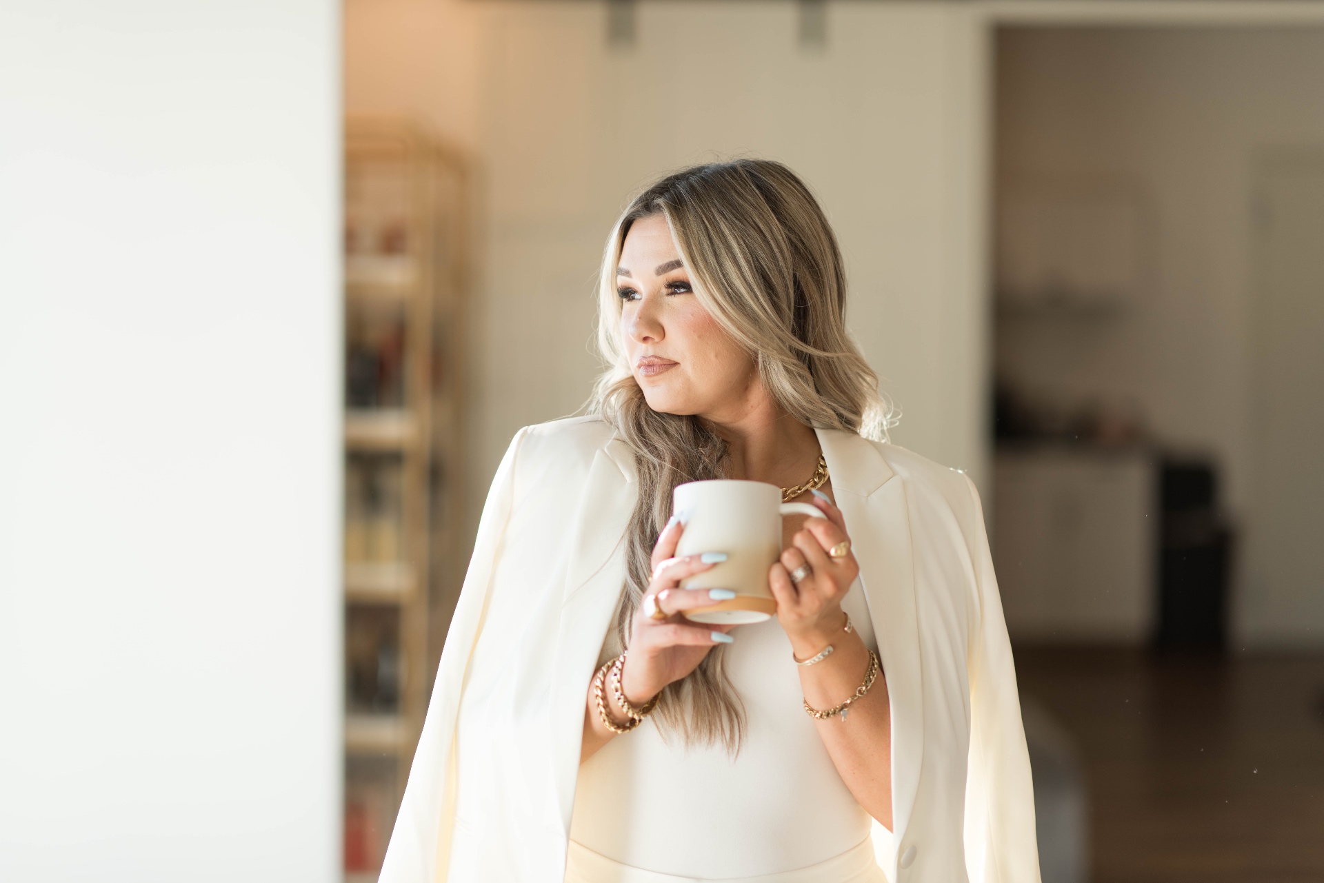 Natalie Breckenridge in an ivory blazer, holding a ceramic mug in soft morning light